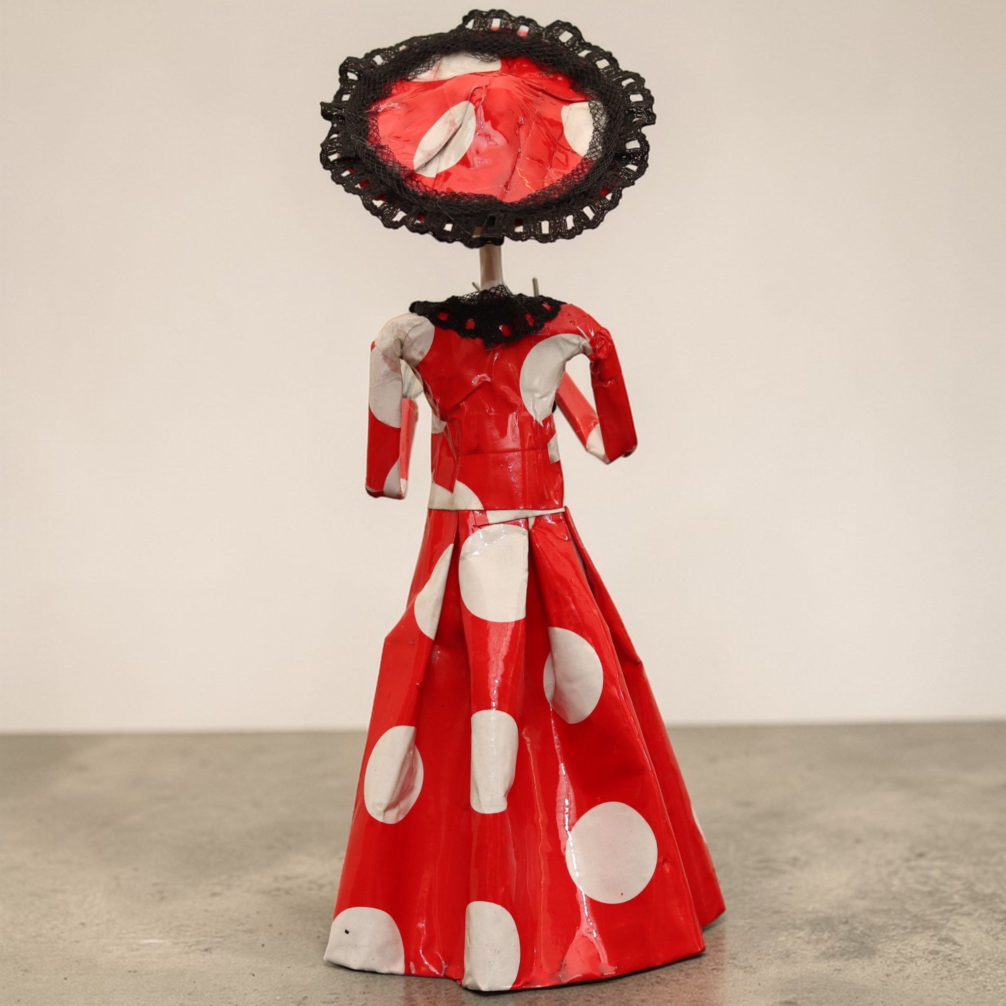 Back view of Catrina figurine showing the wide-brimmed lace hat and pleated red polka dot skirt, handcrafted Mexican Día de los Muertos décor