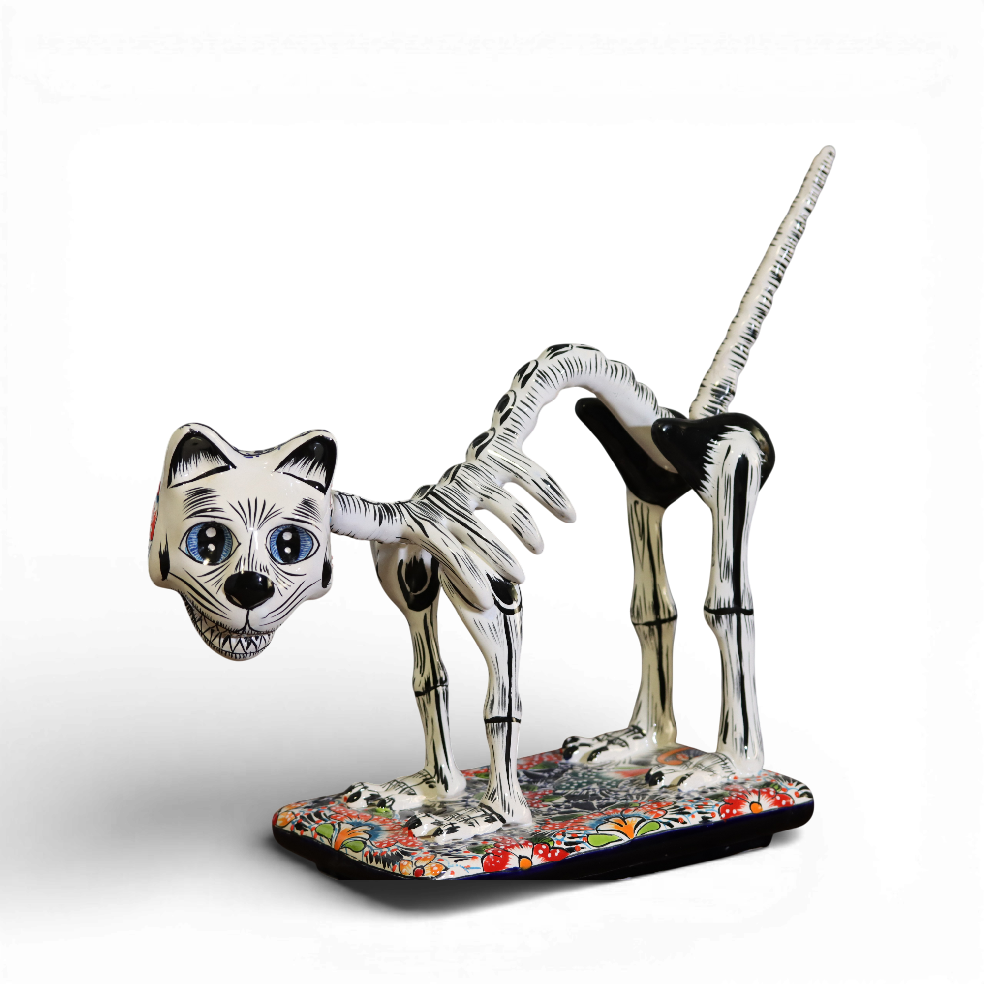 Side view of hand painted Talavera skeletal cat sculpture on colorful base isolated on white background
