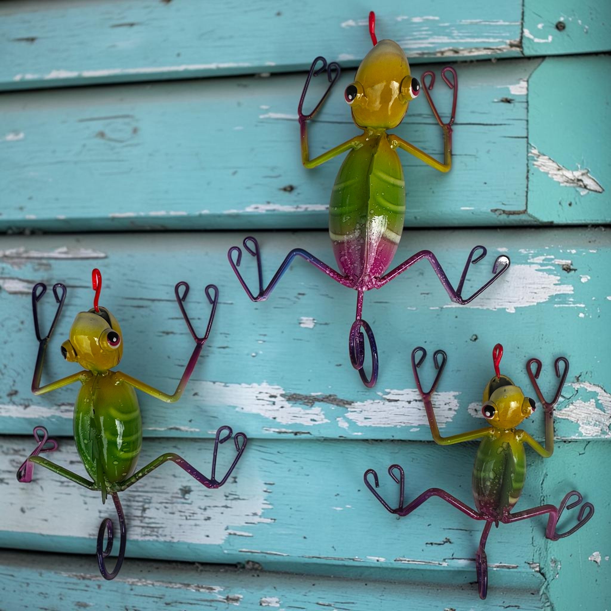 Climbing lizard wall art set of 3 on light teal painted wood, hand-painted Mexican folk art geckos with green bodies and pink accents