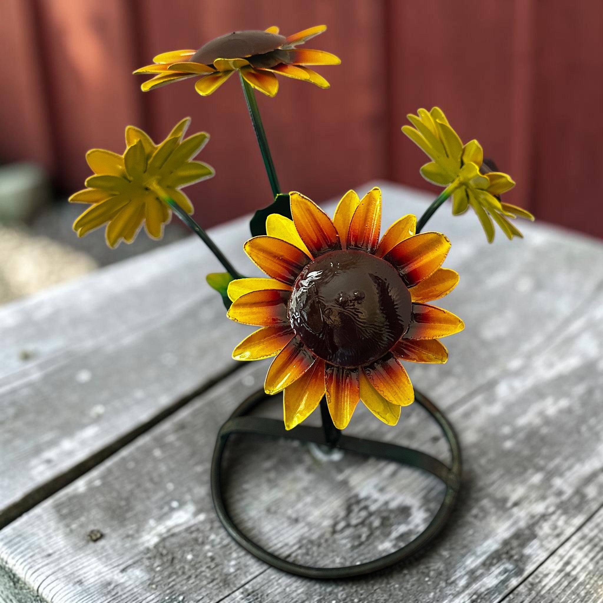 Metal sunflower yard art sculpture with hand-painted yellow petals against weathered red barn wood background, country farmhouse garden decor