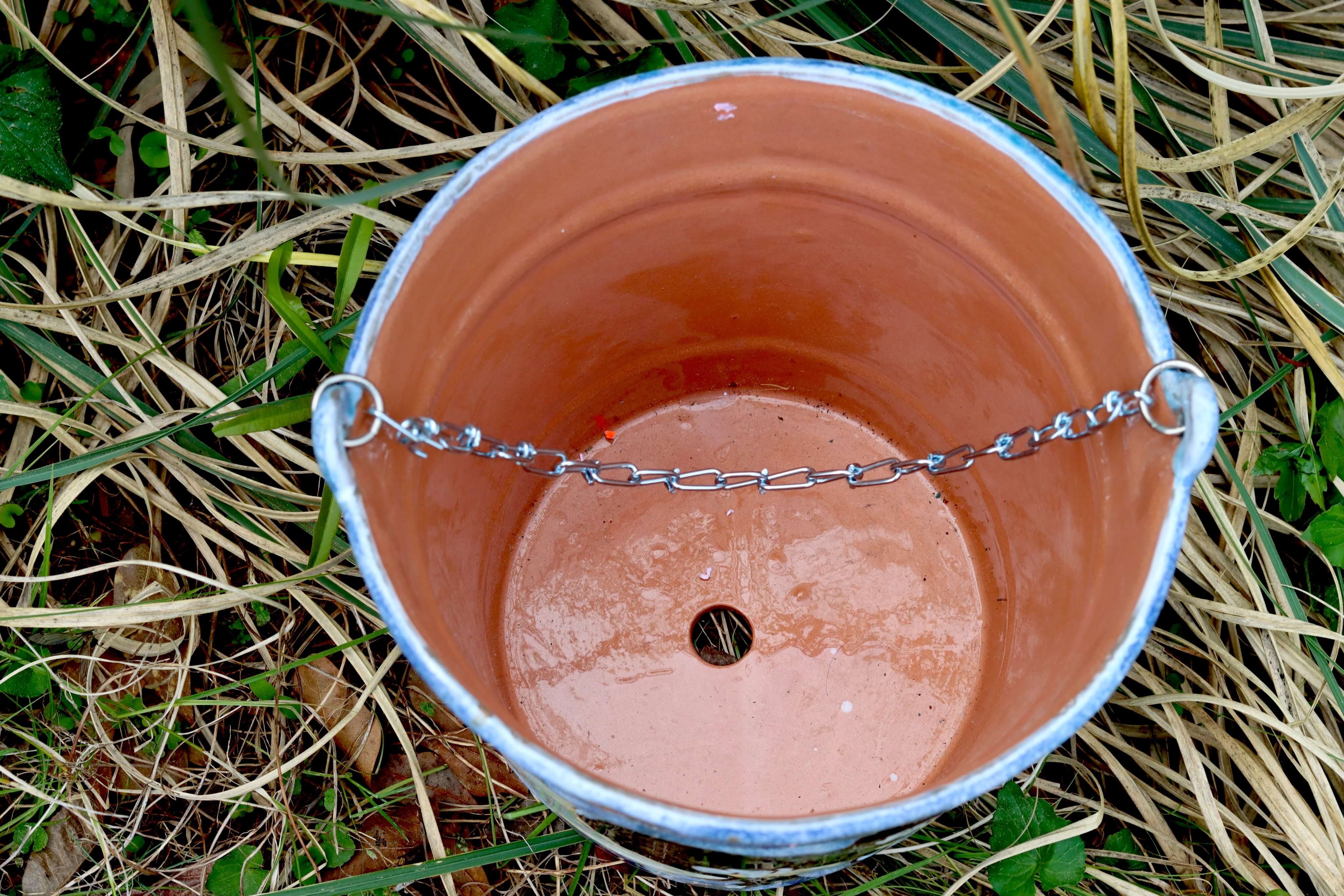 Interior view of hand-painted Guanajuato ceramic planter showing drainage hole and metal chain handle